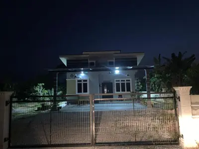 a white house with lights on a fence at night at Homestay D'Kutan Bandar Baharu Kedah in Bandar Baharu