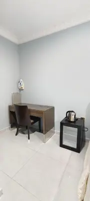a room with a desk and a table and a chair at 3Q Impiana Roomstay Teluk Senangin in Lumut