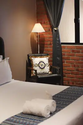 a room with a bed and a chair and a lamp at RARE Heritage House in George Town