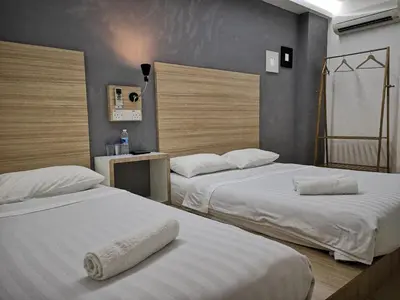 two beds in a hotel room with white sheets at Dragon Door Hotel in Sitiawan