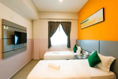 a hotel room with two beds and a tv at Travelland Hotel in Ipoh