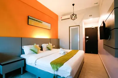 a bedroom with a bed with an orange wall at Travelland Hotel in Ipoh