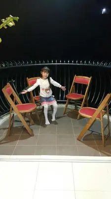 a little girl sitting in between two chairs at Rose Apartment Kea Farm in Cameron Highlands