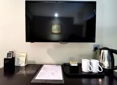 a desk with a television on a wall with a coffee pot at Kimberley Hotel Georgetown in George Town