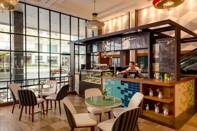 a restaurant with tables and chairs and a woman sitting at a counter at JEN Penang Georgetown by Shangri-La in George Town