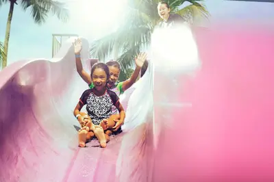 two children sliding down a slide on a pink slide at Hard Rock Hotel Penang in Batu Ferringhi