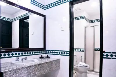 a bathroom with a toilet and a sink and a mirror at Leisure Cove Hotel and Apartments in George Town