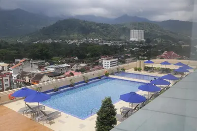a swimming pool with chairs and umbrellas on a building at Novotel Taiping in Taiping