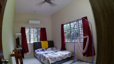 a bedroom with a bed and two windows at Homestay selinsing in Simpang Ampat Semanggol
