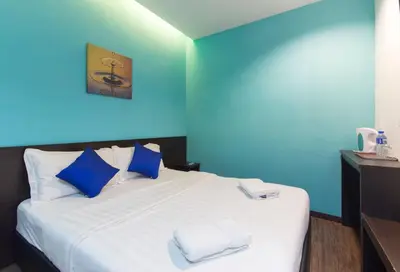 a blue room with a bed with towels on it at Clover Hotel Ipoh in Ipoh