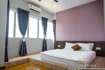 a bedroom with a bed and two windows at Shuang Yang Sekinchan Homestay in Sekincan
