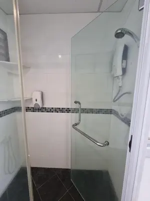 a shower with a glass door in a bathroom at Aloka Seaview Apartment in Batu Ferringhi