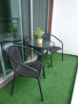 a table and chairs on a balcony with green carpet at Strawberry Homestay in Cameron Highlands