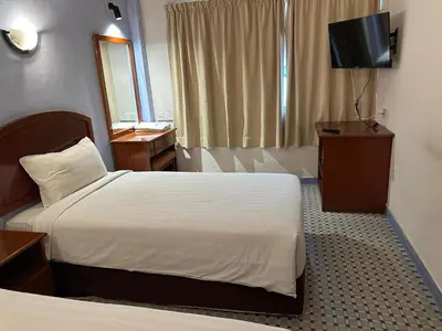 a hotel room with two beds and a television at New Caspian Hotel in Ipoh