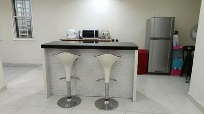 a kitchen with a counter with two silver stools at The Louvre Moslim Homestay Sungai Petani in Sungai Petani