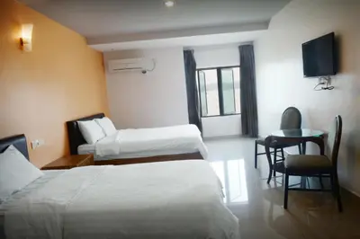 a hotel room with two beds and a table and a television at Brezza Hotel Lumut in Lumut