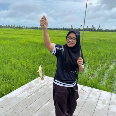 a woman is holding up a bow and arrow at Kurau Inn Boutique Farmstay in Kuala Kurau