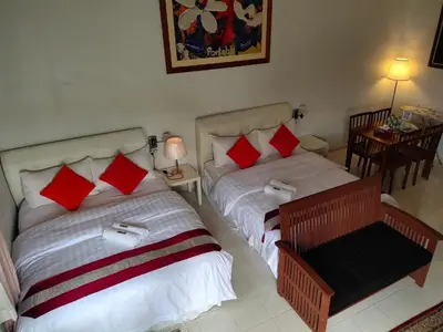 a bedroom with two beds with red and white pillows at Kurau Inn Boutique Farmstay in Kuala Kurau