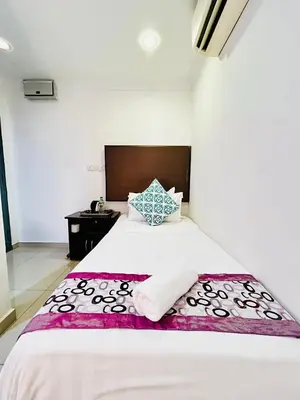a bedroom with a large white bed with a wooden headboard at Hotel Sagittario in Ipoh