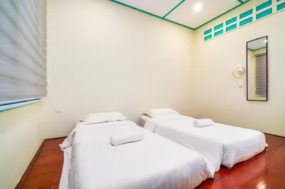 two beds in a room with white walls at Dream & Wander Homestay in Ipoh