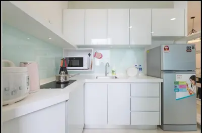 a white kitchen with white cabinets and a refrigerator at Penang Studio Suite in Georgetown in George Town