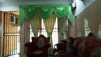 a room with a couch and a window with green curtains at Farzai Homestay in Lumut