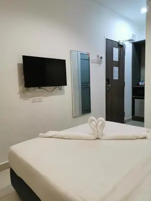 a bedroom with a bed and a flat screen tv at Hotel Alpha in Bukit Mertajam