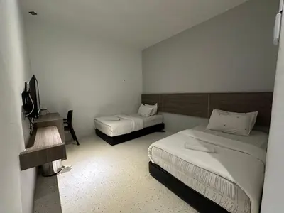 a small room with two beds and a television at WF Motel in Kulim
