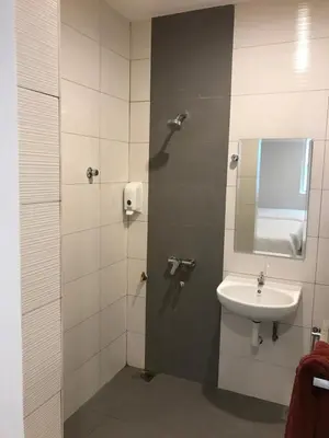 a bathroom with a sink and a shower with a mirror at Brezza Hotel Sitiawan in Sitiawan