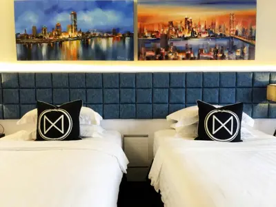two beds in a hotel room with a picture on the wall at M Roof Hotel & Residences in Ipoh