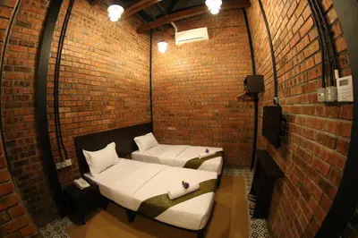 two beds in a room with a brick wall at JQ Ban Loong Boutique Hotel in Ipoh