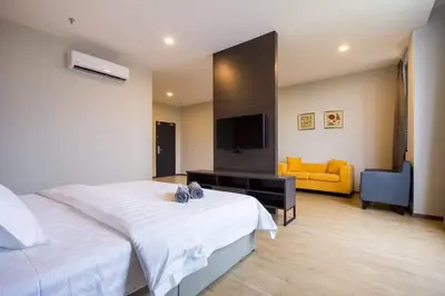 a bedroom with a white bed and a yellow couch at OMG Hotel in Simpang Ampat