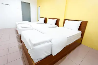 a row of white beds in a room at Lux Hotel in Teluk Intan