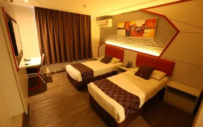 a hotel room with two beds and a television at Golden Nasmir Hotel in Bukit Mertajam