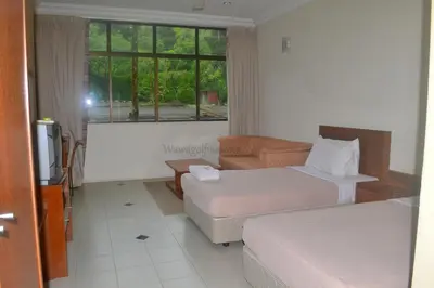 a hotel room with two beds and a couch and a window at Wawa's Golf View Inn in Taiping