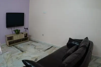 a black leather couch in a living room with a television at Taiping Cozy Homestay in Taiping
