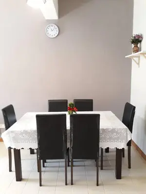 a dining room table with chairs and a clock on the wall at 5-MINS WALK TO BEACH WITH POOL, Batu Ferringhi in Batu Ferringhi