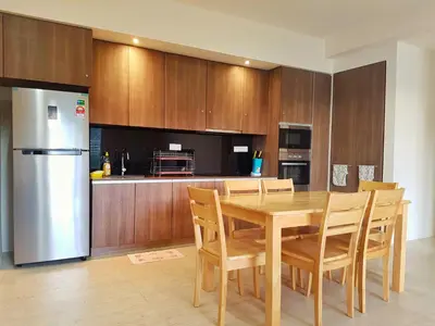 a kitchen with a table and a stainless steel refrigerator at By The Sea Duplex Condo in Batu Ferringhi