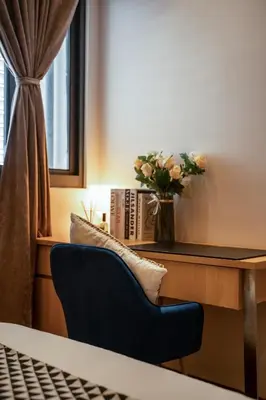 a chair in front of a desk with a vase of flowers at Summer Tree Hotel Penang in George Town