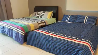 two beds sitting next to each other in a room at Woon Homestay in Balik Pulau