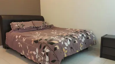 a bedroom with a bed with a brown comforter at Woon Homestay in Balik Pulau
