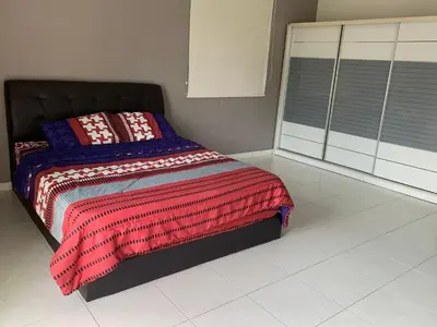 a bedroom with a bed with a colorful blanket on it at Woon Homestay in Balik Pulau