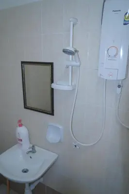 a bathroom with a shower and a sink and a mirror at ARUWDA Homestay in Ipoh