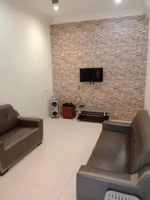a living room with a couch and a tv on a brick wall at ARUWDA Homestay in Ipoh