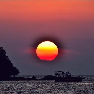 a boat in the ocean with a sunset at Pangkor Holiday Home in Pangkor