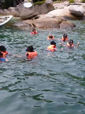 a group of people swimming in the water at Pangkor Holiday Home in Pangkor