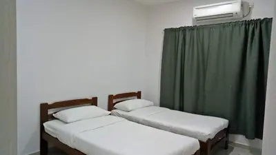 two beds in a room with a green curtain at Pangkor Holiday Home in Pangkor