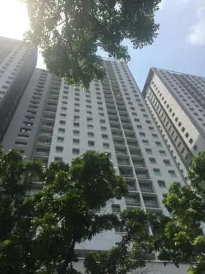 a tall white building with trees in the foreground at Muslim Homestay Apartment in George Town