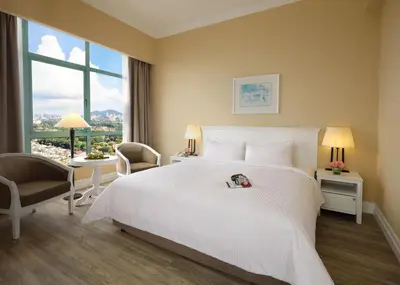 a hotel room with a large white bed and a window at Berjaya Penang Hotel in George Town