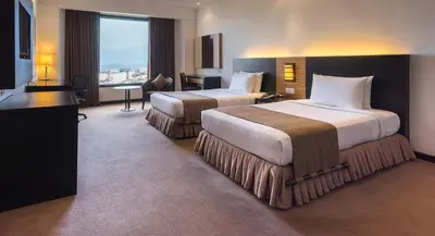 a hotel room with two beds and a television at Bayview Hotel Georgetown Penang in George Town
